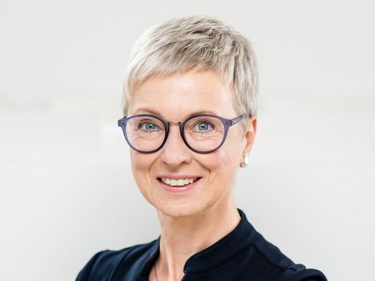 Porträtfoto einer Frau mit kurzen blonden Haaren und Brille 
