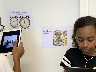 Zwei Kinder/ Jugendliche mit Tabletts und Kabel-Kopfhörern
