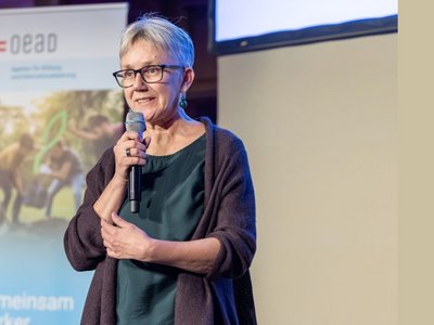 Frau mit Mikrophon in der Hand sprechend im Hintergrund Roll-Up