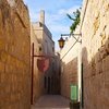 Street in an old mediterranean town eine enge Gasse eingerahmt von hohen Steinmauern
