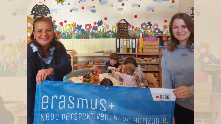 Zwei Frauen halten einen Erasmus+ Banner in die Kamera und lachen 