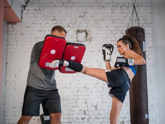 1279840761 Junge Frau beim Boxtraining, kickt gerade mit Fuß