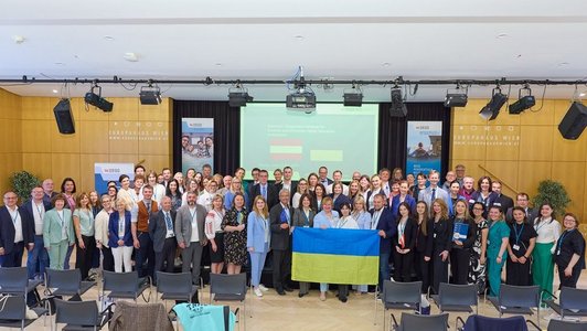 Gruppenbild mit allen Teilnehmern der Veranstaltung. In der Mitte ist eine ukrainische Flagge zu sehen