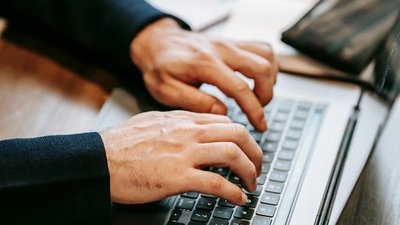 Zwei Hände tippen auf einer Laptop-Tastatur.