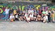 25 Jugendliche stehen vor einem Graffiti 
