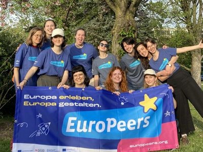 Gruppe junger Menschen hält EuroPeers Flagge in der Hand