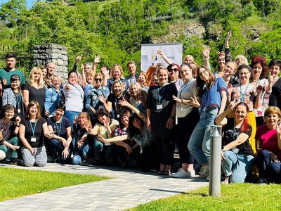 Foto aller Teilnehmerinnen und Teilnehmer des eTwinning-Donauraumseminars 2023. In etwas 50 Teilnehmer/innen stehen mit freudigem Blick und teils gehobenen Armen vor einem grünen Weinhügel.