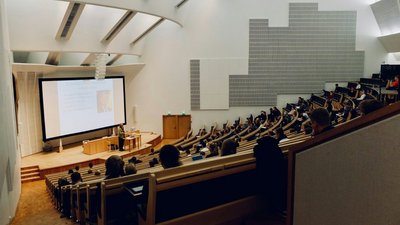 Menschen, die auf Bänken im Hörsaal sitzen