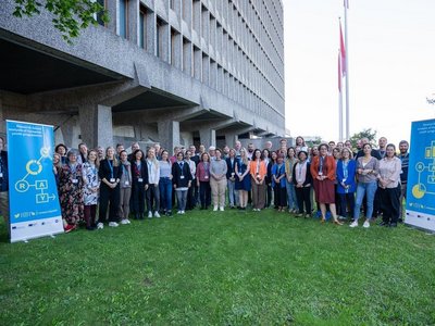 Eine große Gruppe an Menschen steht auf einer Wiese und schaut in die Kamera