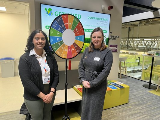 Zwei Frauen vor einem Glücksrad mit den Zielen für nachhaltige Entwicklung der Vereinten Nationen