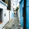 Blick auf eine kleine Gasse mit blauen Häusern.