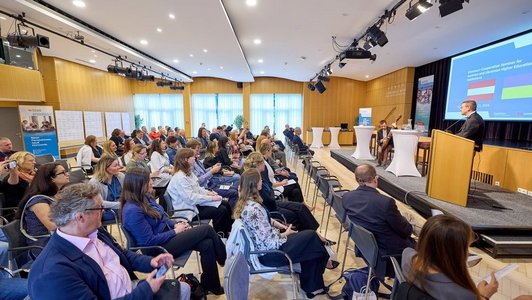 Das Publikum einer Podiumsdiskussion in einer voll besetzten Veranstaltungshalle