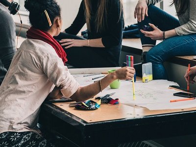 Fünf Personen sitzen um einen Tisch und diskutieren.