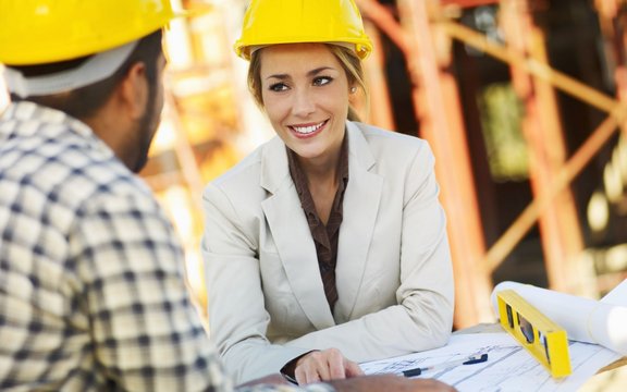 Frau und Mann mit Bauhelmen auf einer Baustelle