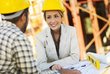 Frau und Mann mit Bauhelmen auf einer Baustelle